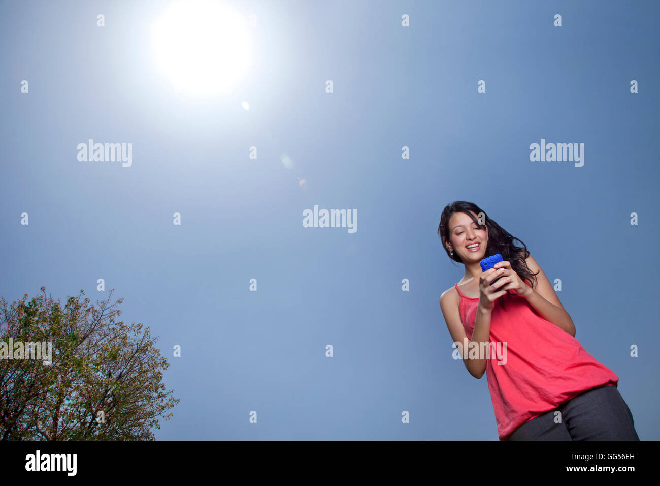Basso angolo di visione della donna per la messaggistica di testo in una giornata di sole Foto Stock