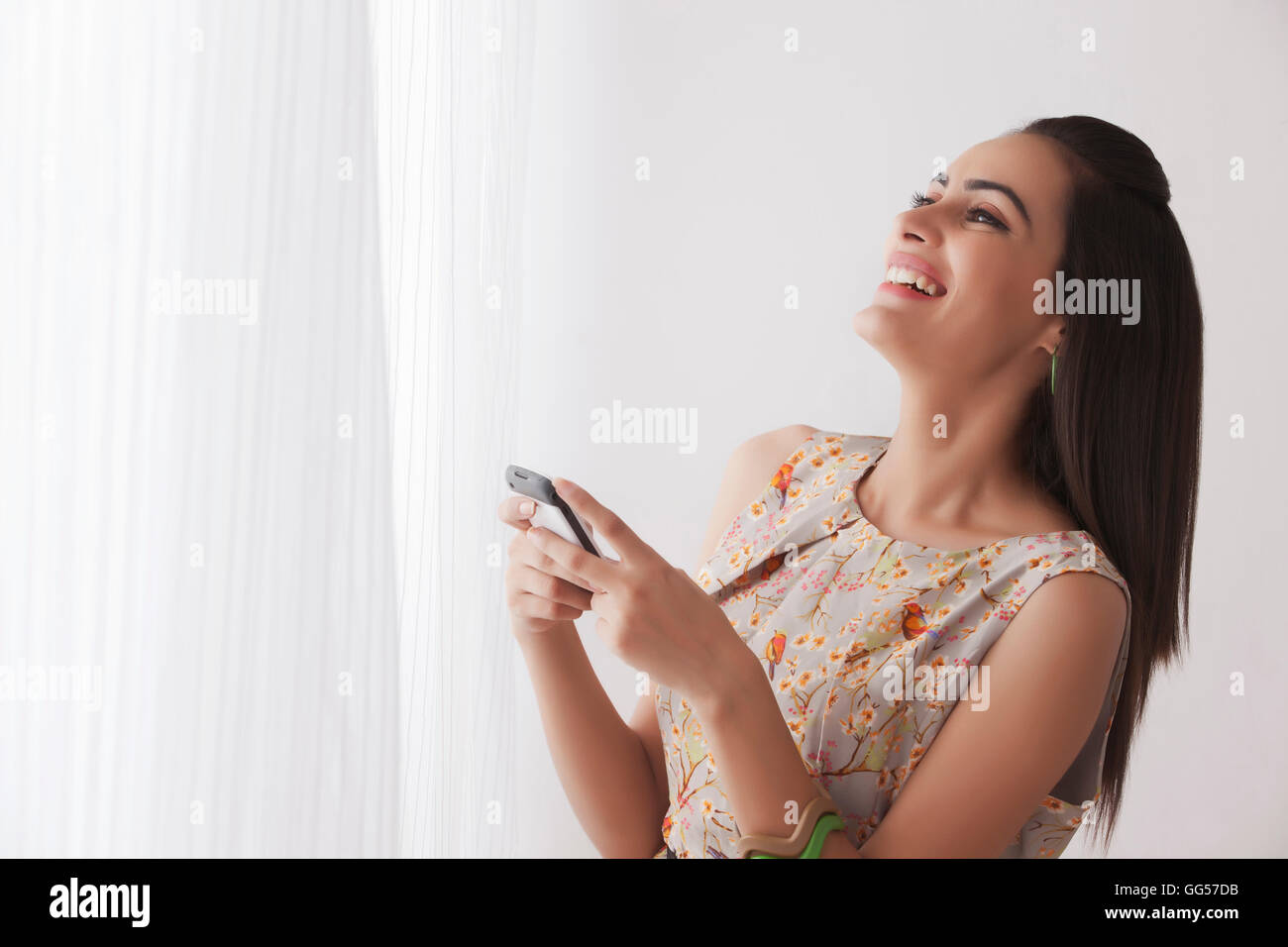 Allegro giovane donna alla messaggistica di testo da tendine Foto Stock