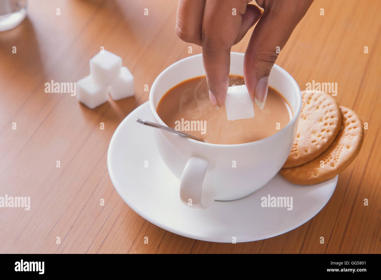 Immagine ritagliata della donna con aggiunta di zucchero di cubo per tè Foto Stock
