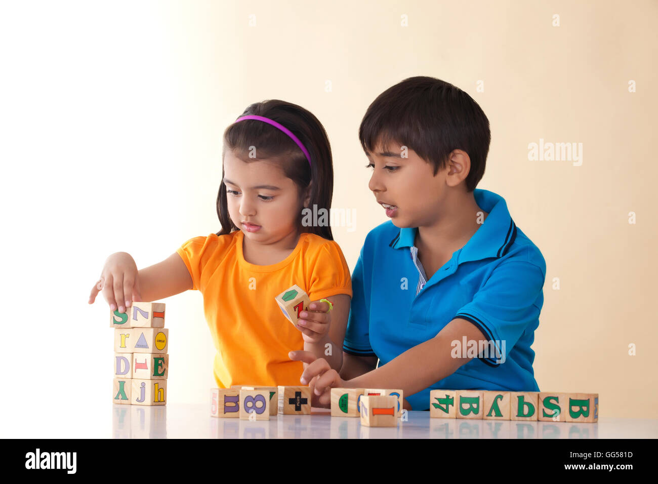 Fratello e Sorella gioca con blocchi contro sfondo colorato Foto Stock