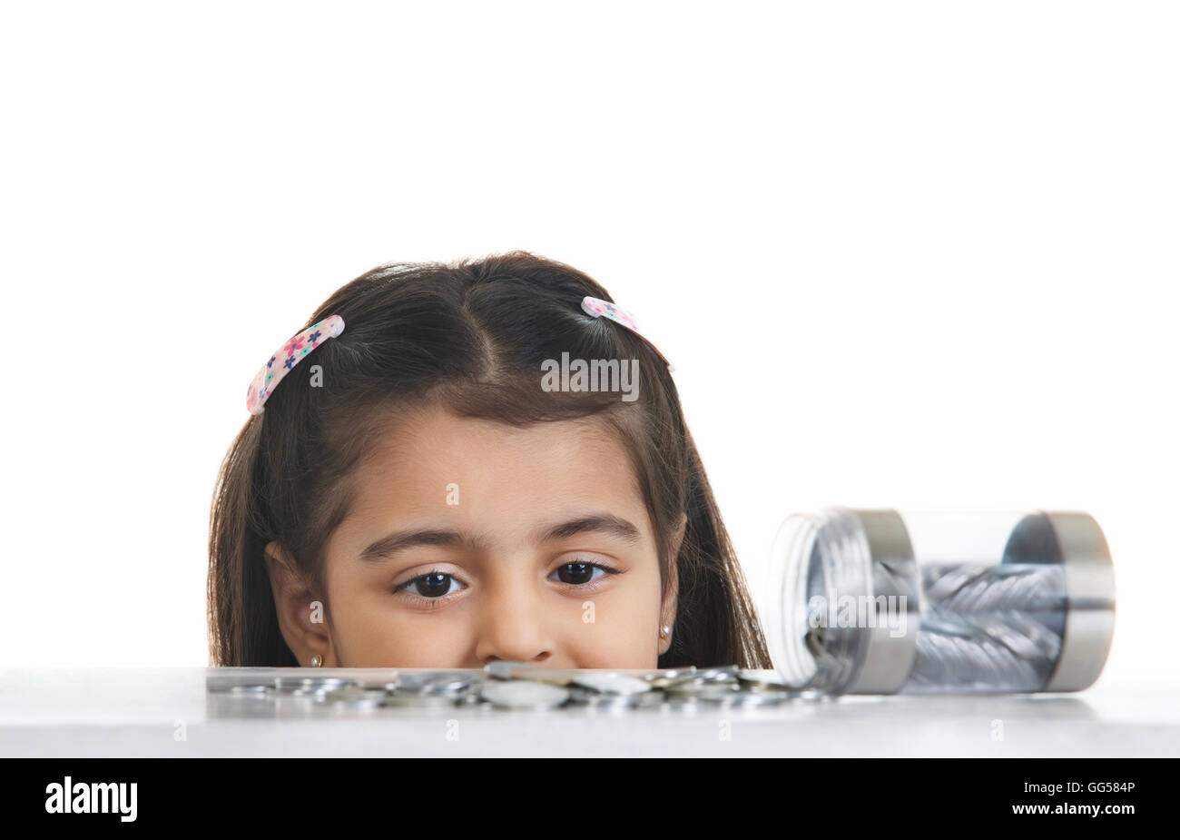 Immagine ritagliata della ragazza guardando le monete indiano versato sul tavolo contro uno sfondo bianco Foto Stock