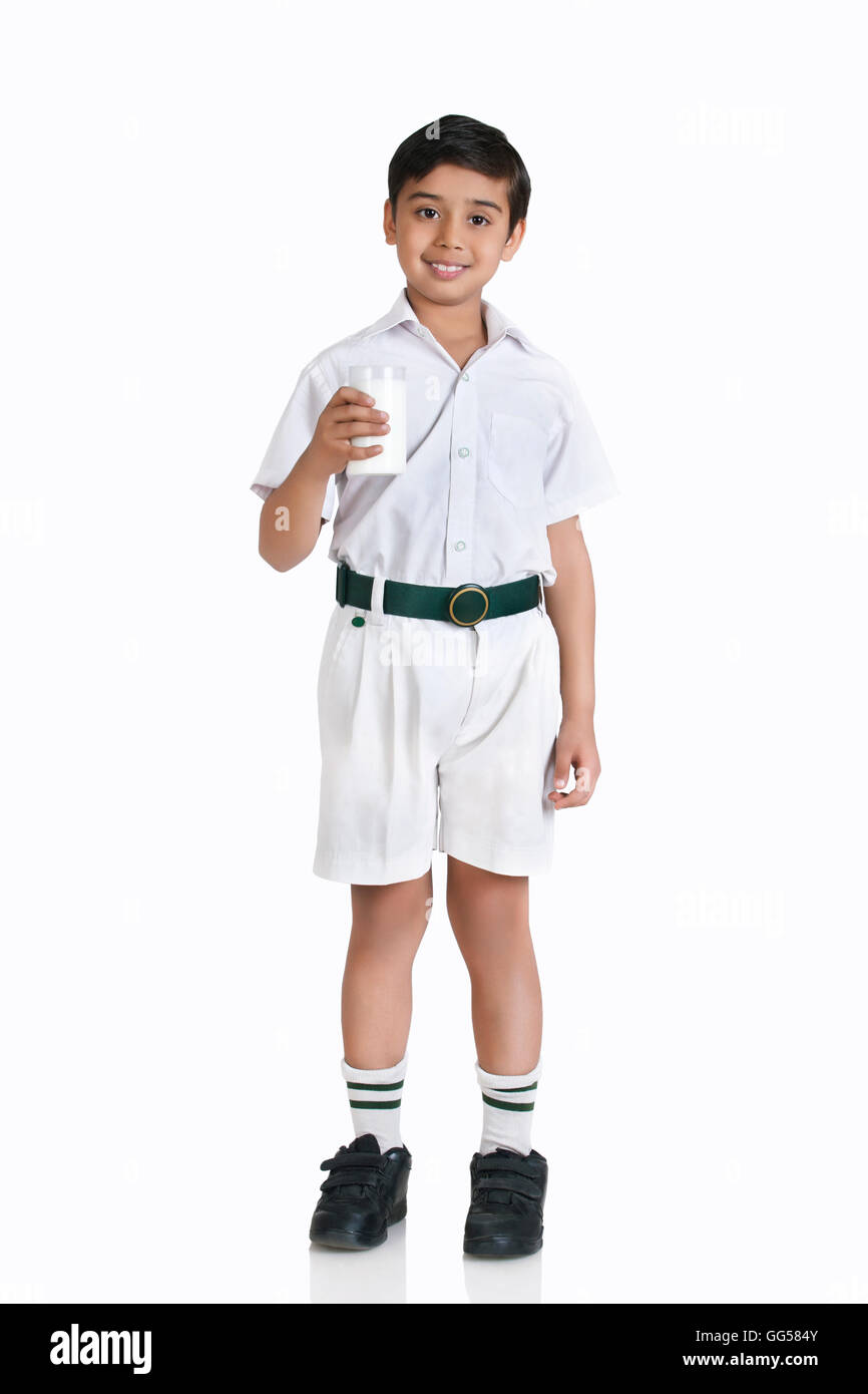 A piena lunghezza Ritratto di ragazzo in uniforme scolastica tenendo il latte su sfondo bianco Foto Stock
