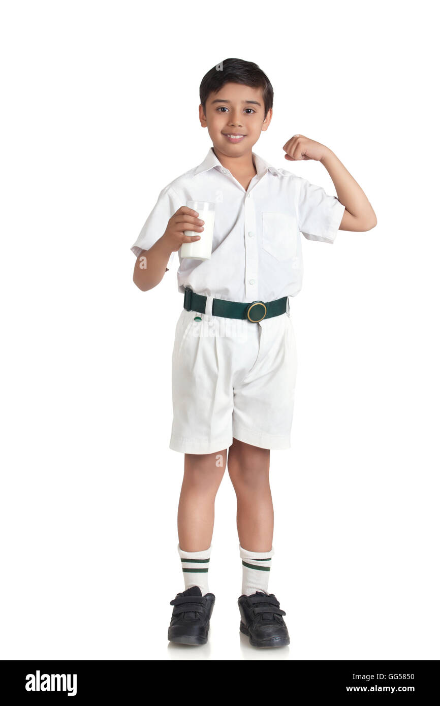 Ritratto di ragazzo in uniforme scolastica flettendo i muscoli mentre si tiene il latte su sfondo bianco Foto Stock