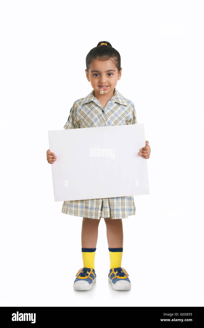 A piena lunghezza ritratto della cute girl in uniforme scolastica azienda targhetta in bianco su sfondo bianco Foto Stock