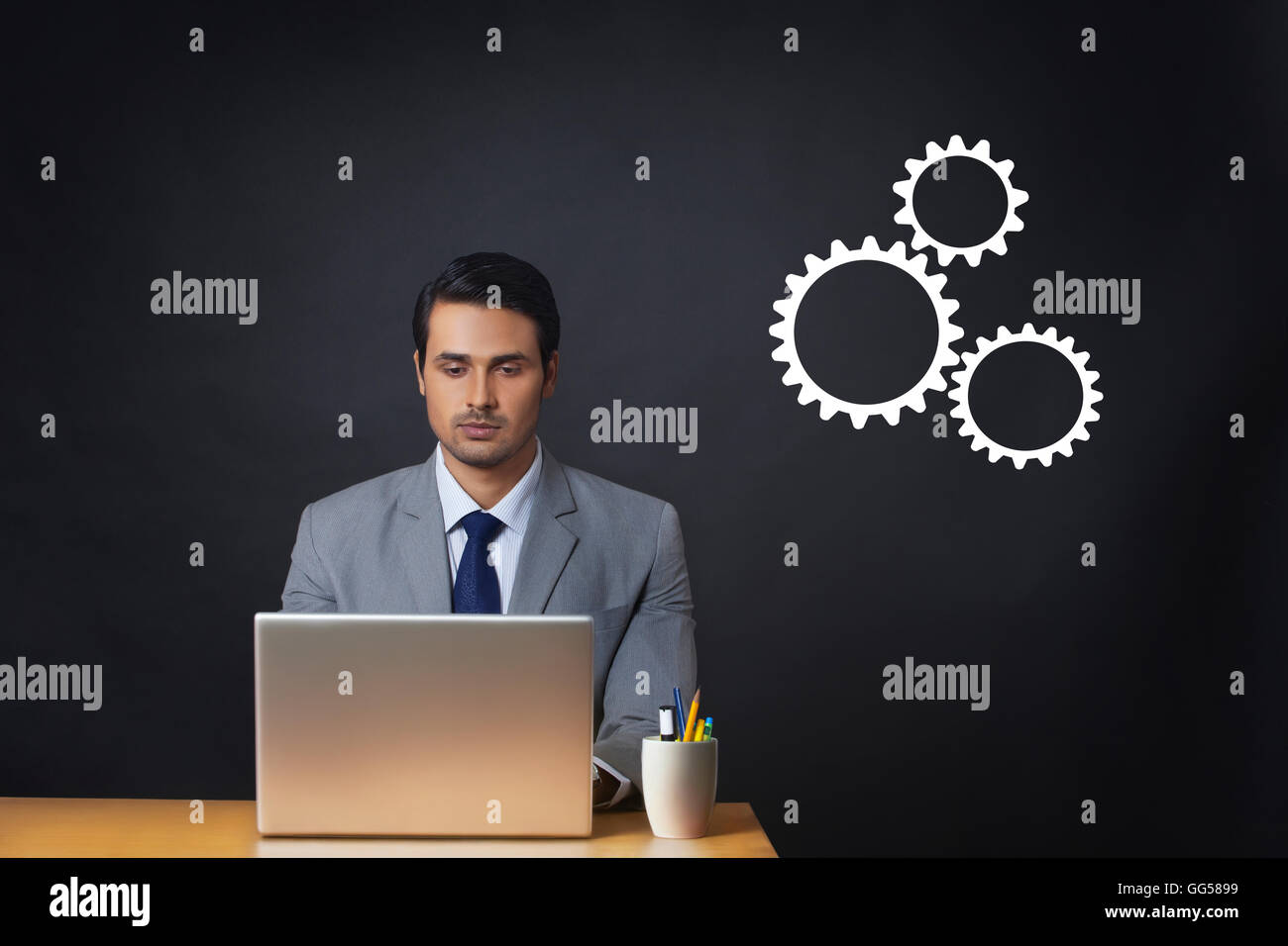 Generati digitalmente immagine dell uomo d affari utilizzando il portatile in ufficio con ingranaggi Foto Stock