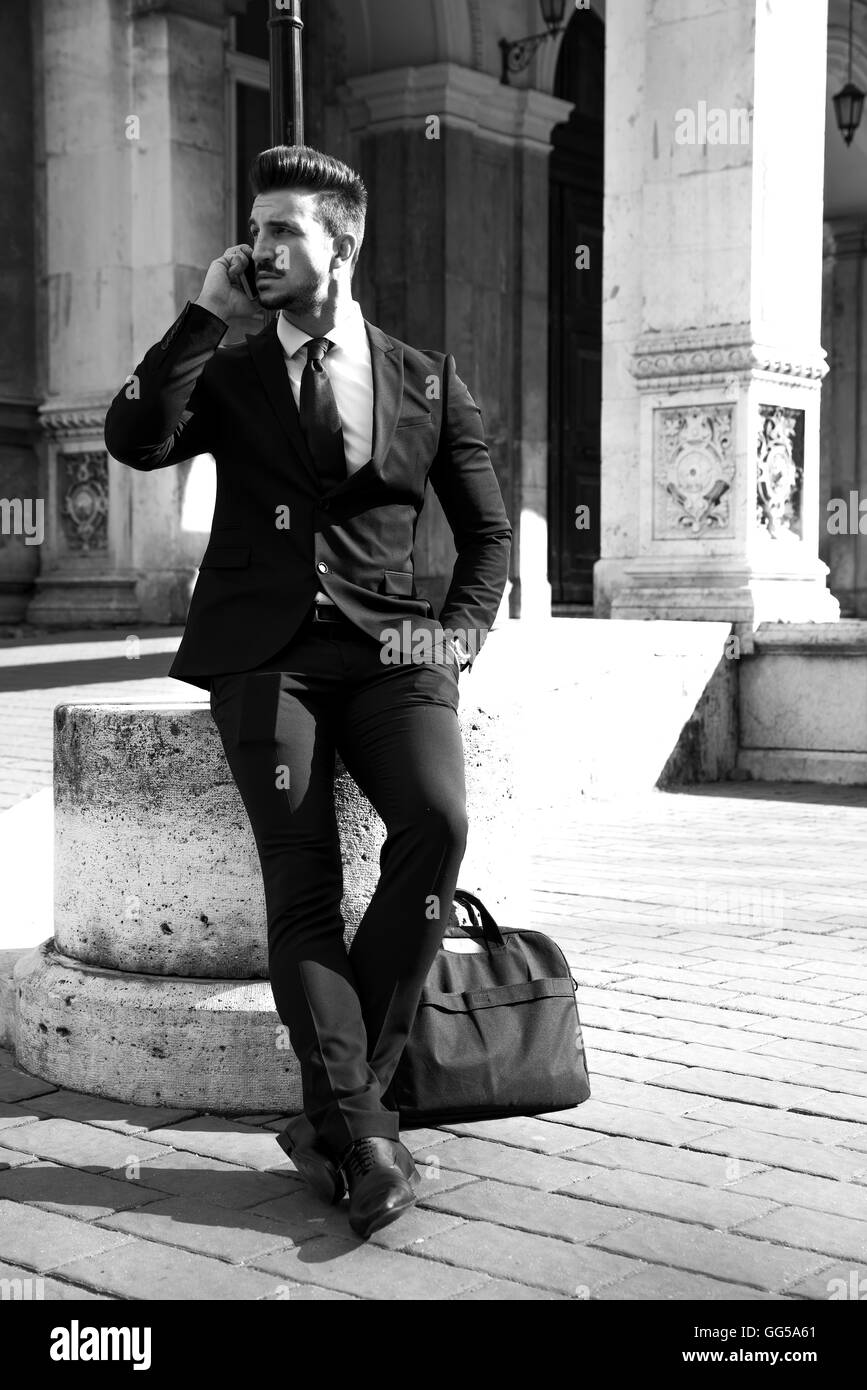 Ritratto in bianco e nero di un uomo di affari sulla strada a parlare su uno smartphone in una città europea. Foto Stock