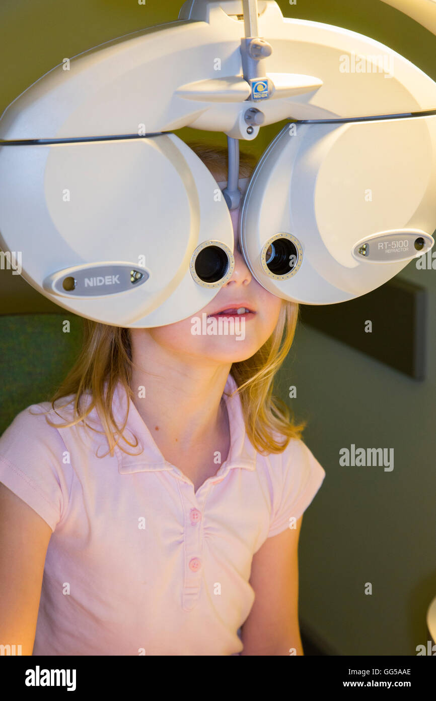 Cinque o sei anni / 5 o 6 anni ragazza impresa / tenendo / avente un occhio test / i suoi occhi testati (con un rifrattore Nidek) REGNO UNITO Foto Stock