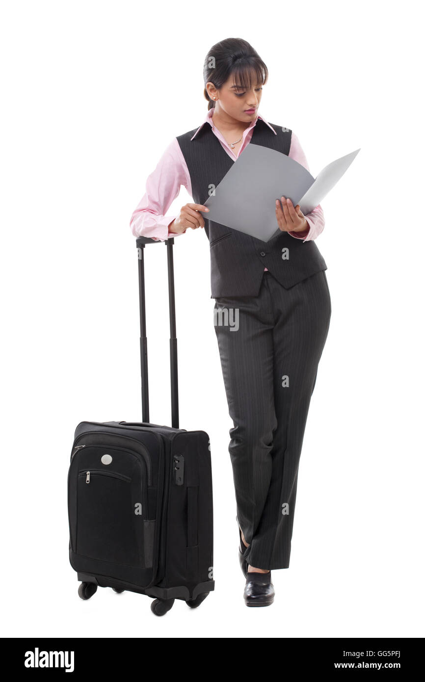 Lunghezza completa di una giovane imprenditrice con bagagli documento di lettura Foto Stock