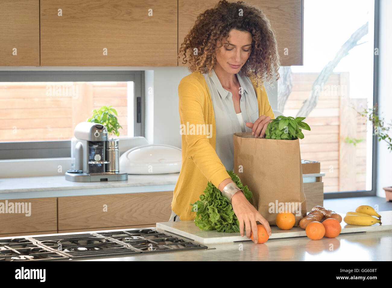 Donna di prendere da mangiare in un sacchetto di carta in cucina Foto Stock
