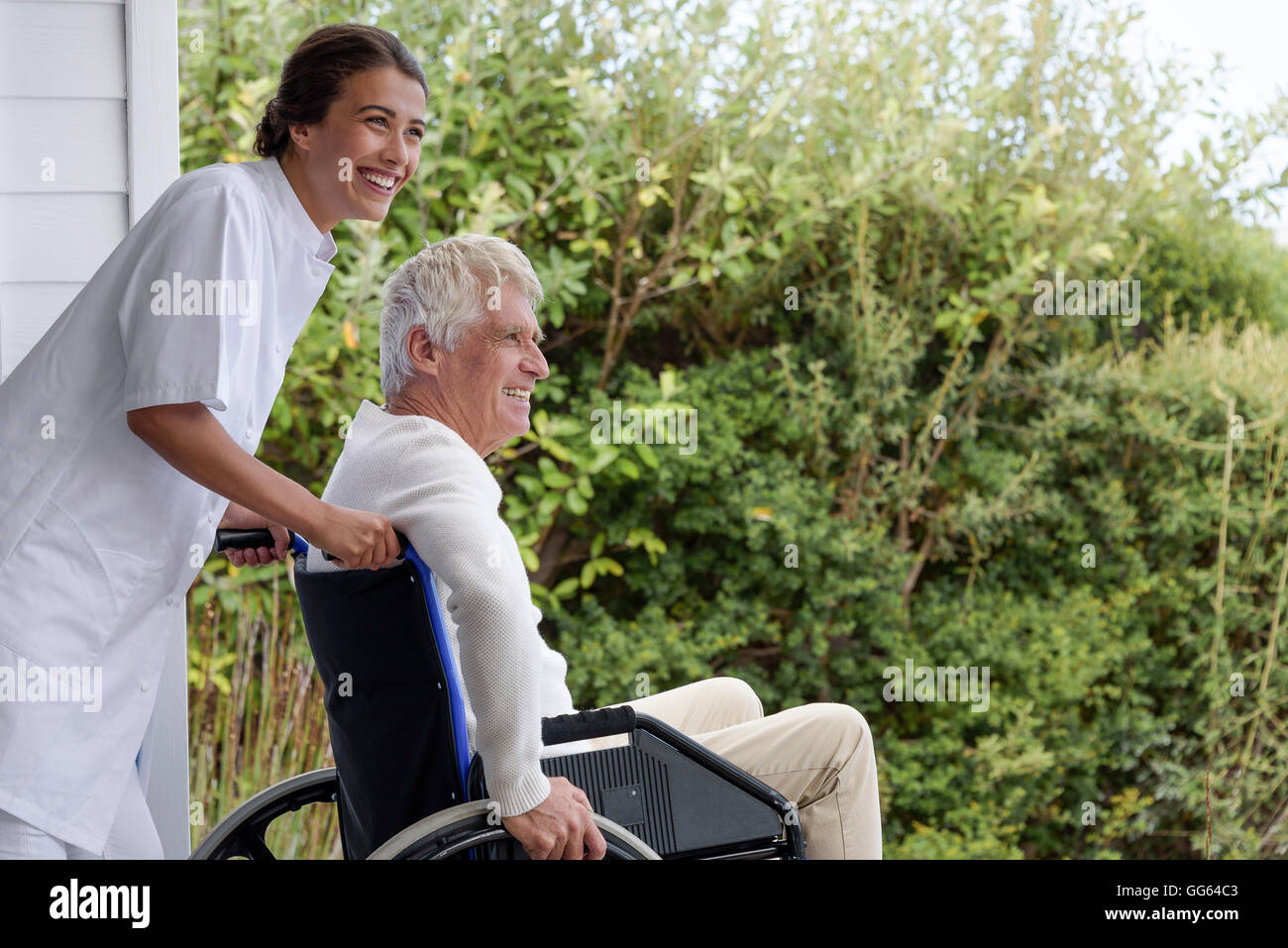 Infermiera femmina assistere senior uomo in sedia a rotelle sulla veranda Foto Stock
