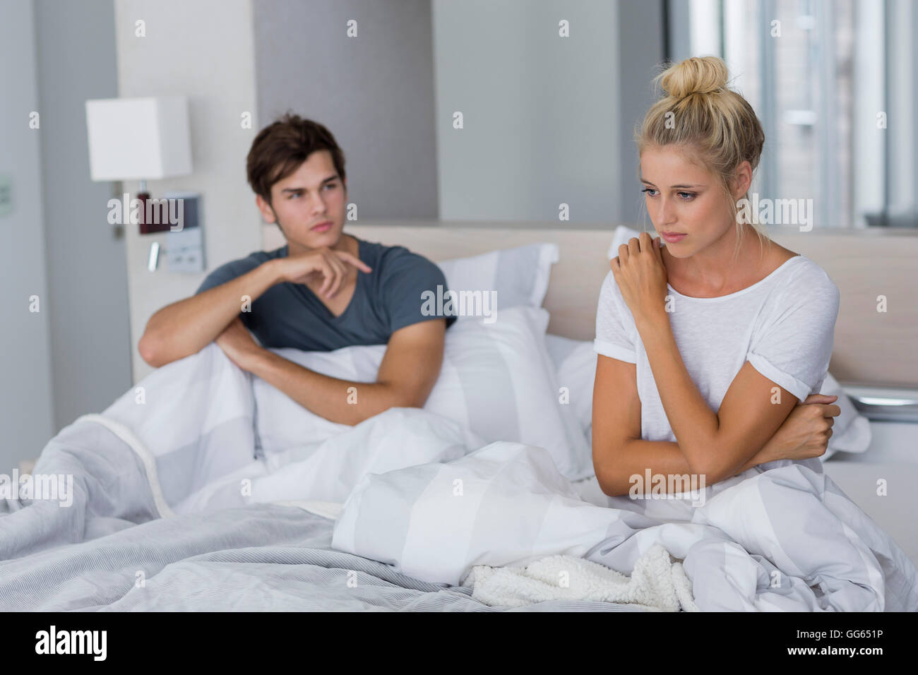 Coppia giovane seduto sul letto con difficoltà di relazione Foto Stock