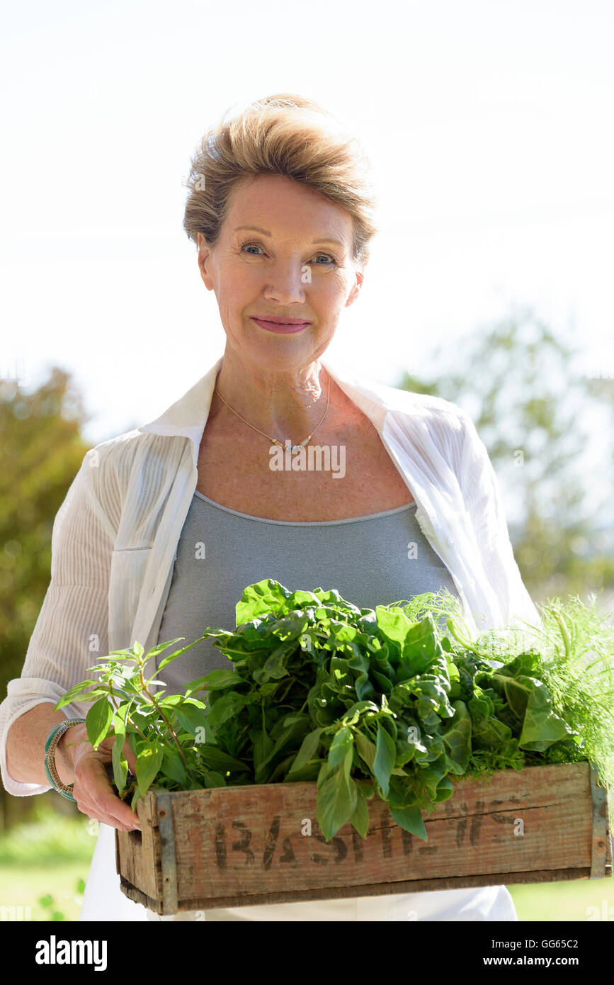 Felice senior donna cassa portante di verdura a foglia Foto Stock