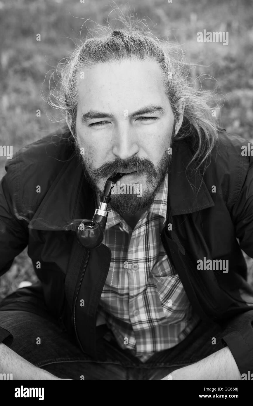 Uomo asiatico fumare una tubazione, in bianco e nero foto verticale con il fuoco selettivo Foto Stock