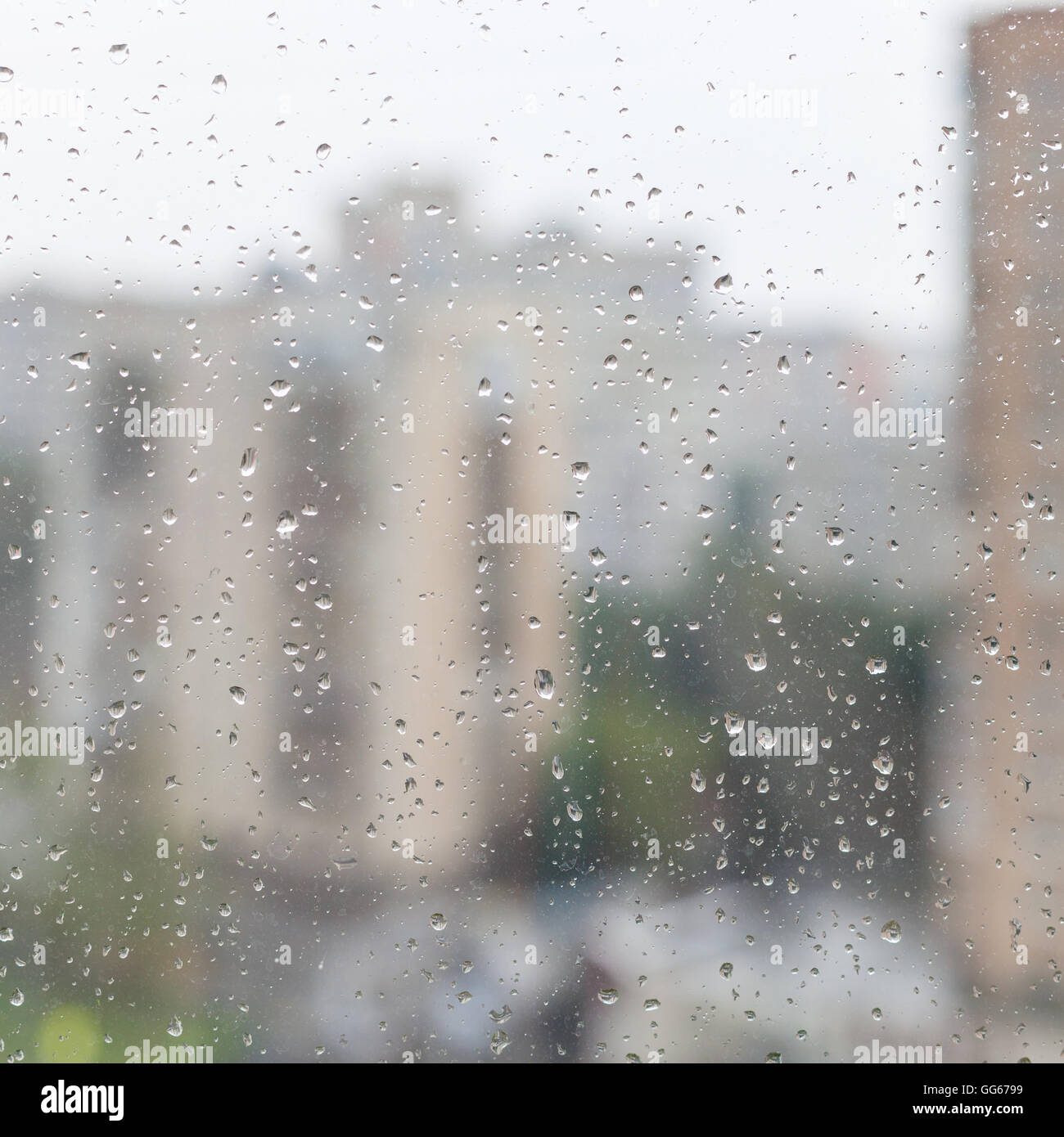 Gocce di pioggia sul vetro di una finestra e sfocata case urbane sullo sfondo Foto Stock
