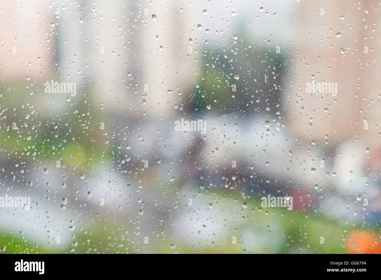 Le gocce di pioggia sul vetro del finestrino e sfocata quartiere residenziale sullo sfondo Foto Stock