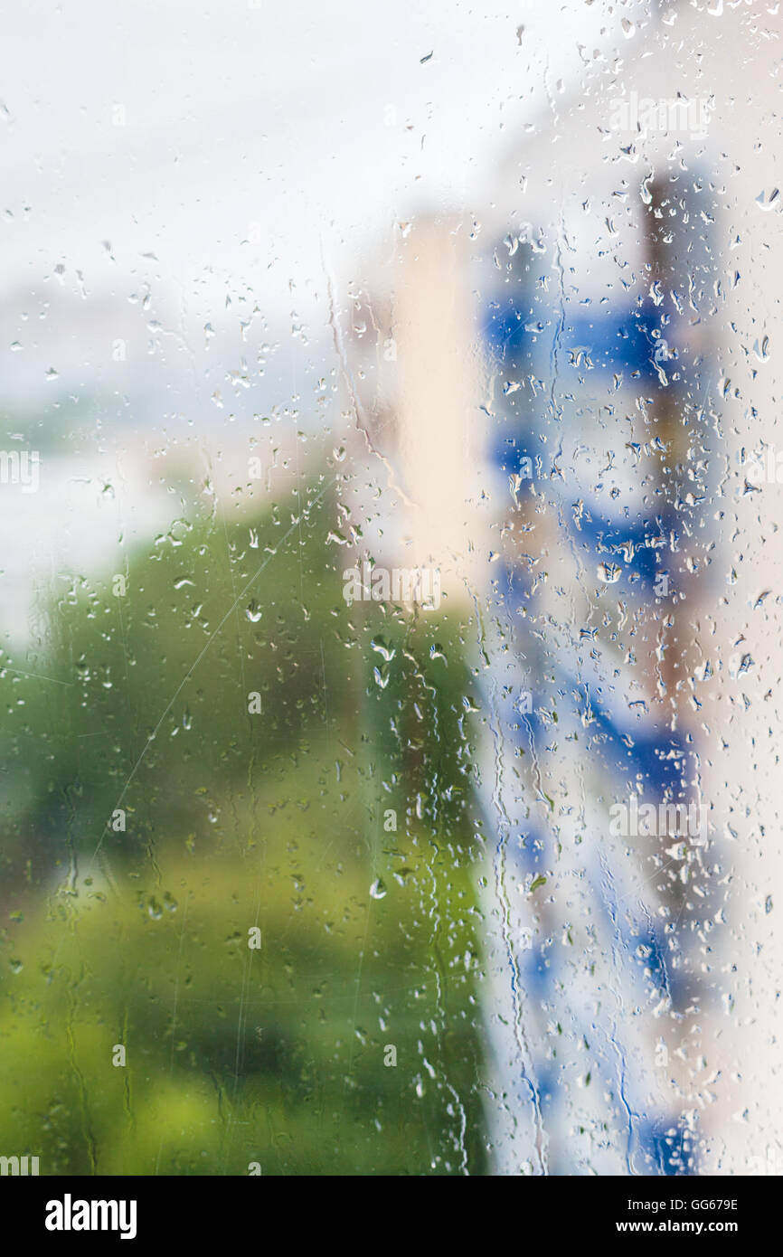 Le gocce di pioggia sulla finestra e sfocata appartamento case sullo sfondo Foto Stock