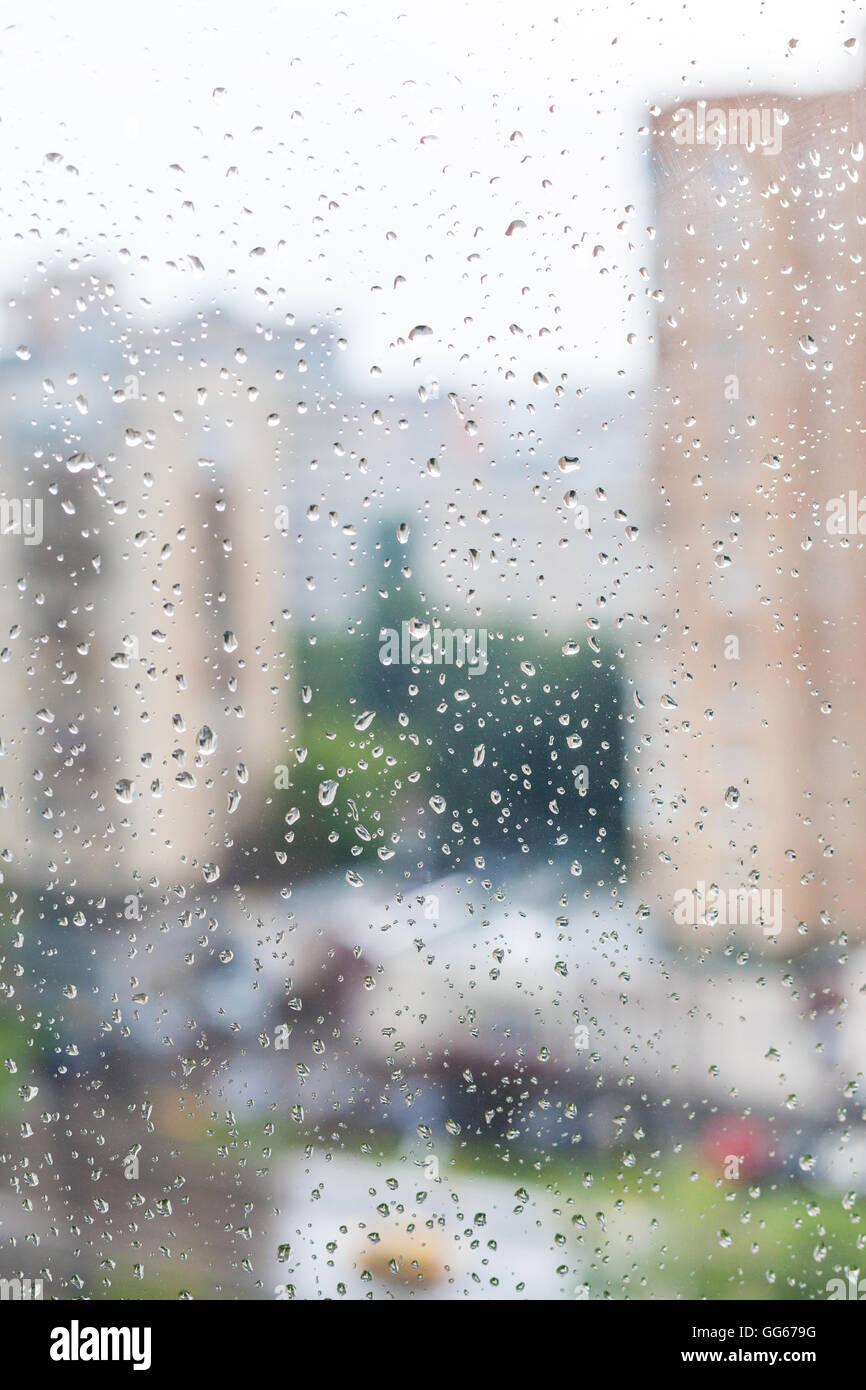 Gocce di pioggia sulla finestra e sfocata skyline sullo sfondo Foto Stock