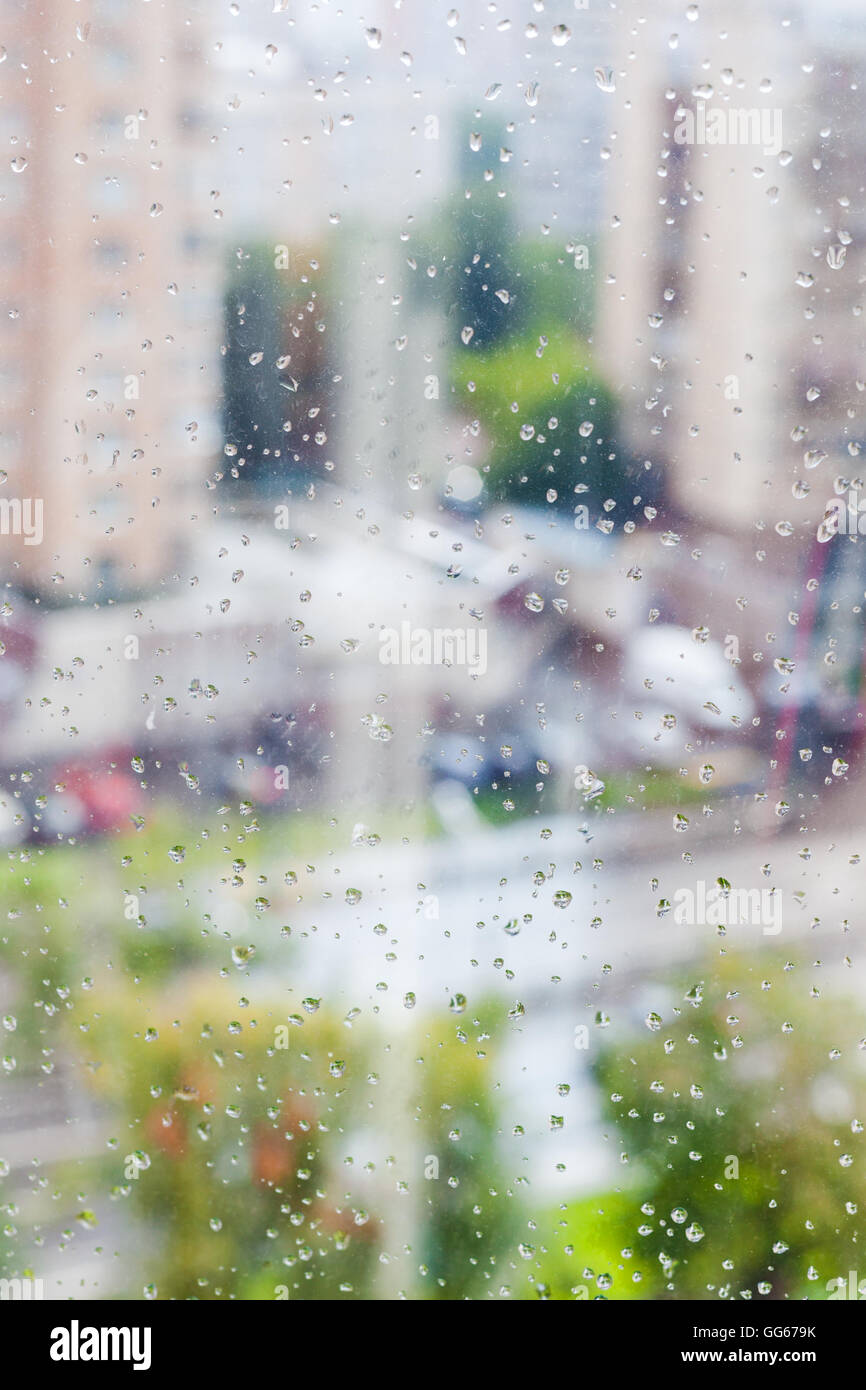 Gocce di pioggia sul vetro del finestrino e sfocata cityscape sullo sfondo Foto Stock