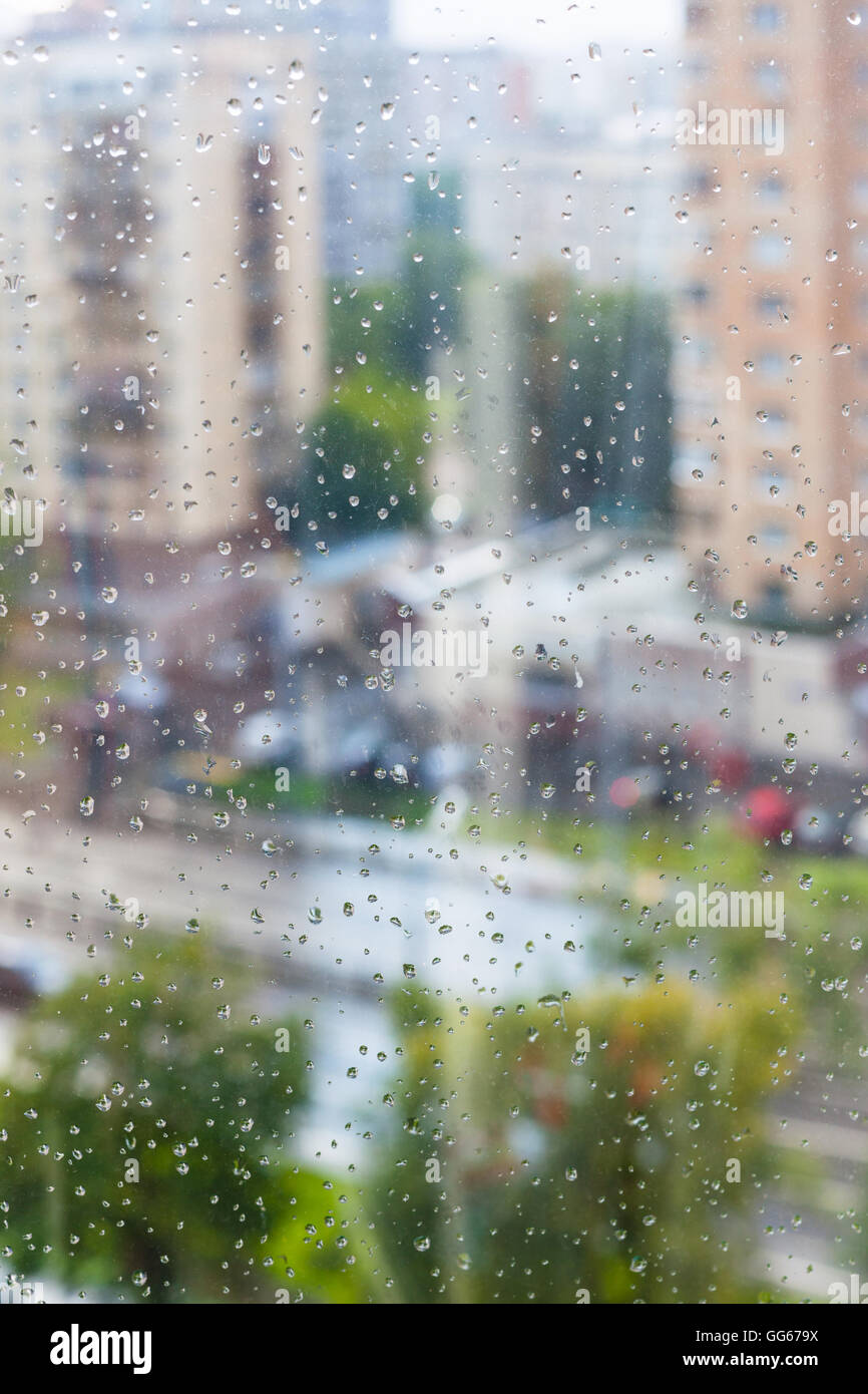 Gocce di pioggia sul vetro del finestrino e sfocata street sullo sfondo Foto Stock