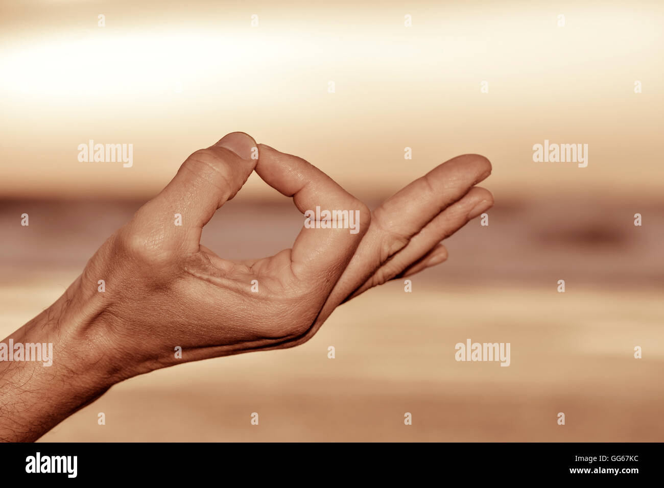 Primo piano di un giovane uomo meditando con le sue mani in gyan mudra all'aperto Foto Stock