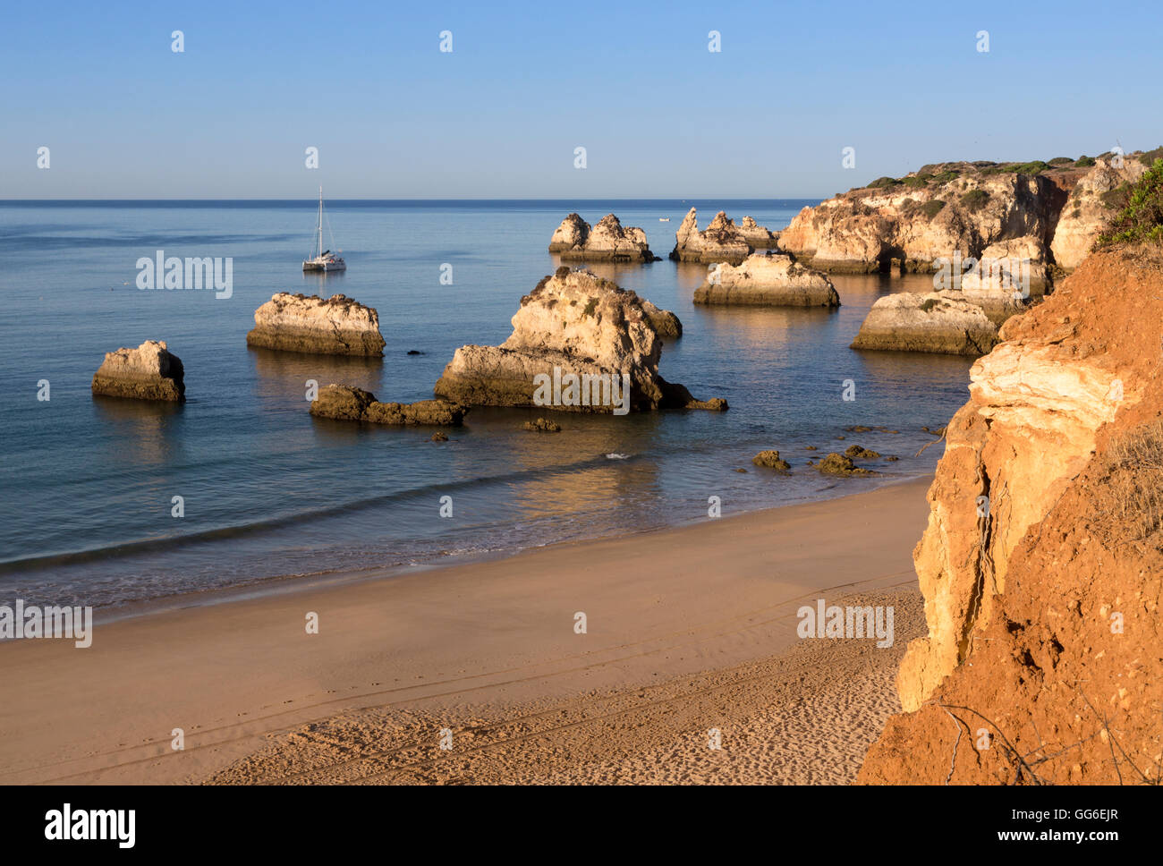 Vista della spiaggia di sabbia fine bagnata dall'oceano blu all'alba, Praia do Alemao, Portimao, distretto di Faro, Algarve, PORTOGALLO Foto Stock