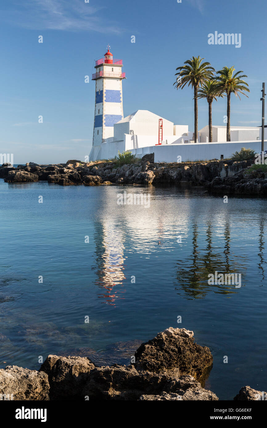 Il faro si riflette nell'acqua blu sotto il cielo estivo blu, Cascais e la costa di Estoril, Lisbona, Portogallo, Europa Foto Stock