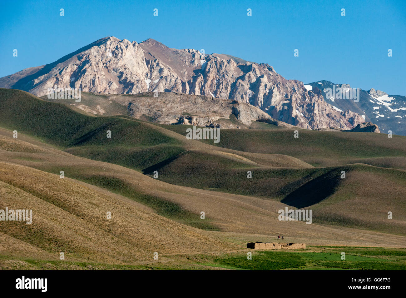 Un distante casa nelle praterie con vedute delle montagne in distanza, provincia di Bamiyan, Afghanistan, Asia Foto Stock