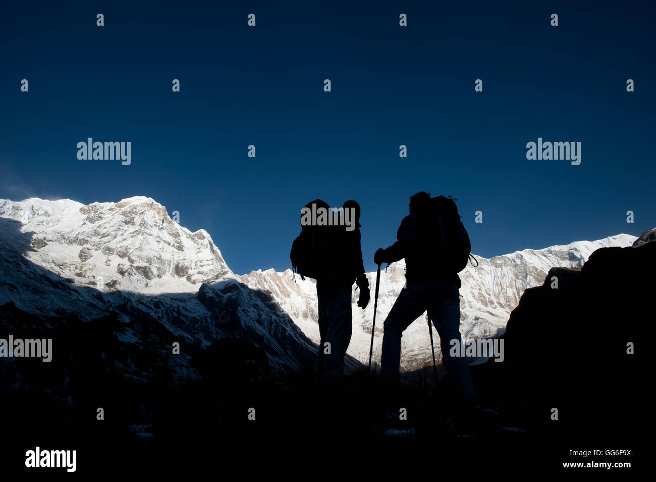 Trekking sulla loro strada verso il basso dalla base di Annapurna camp con vedute di Annapurna 1 nella distanza, Himalaya, Nepal, Asia Foto Stock