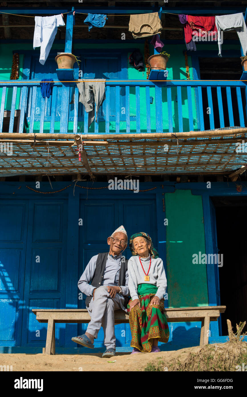 Una vecchia coppia nepalese indossando vestiti tradizionali sedersi al di fuori della loro casa in Diktel, Khotang District, Nepal, Asia Foto Stock