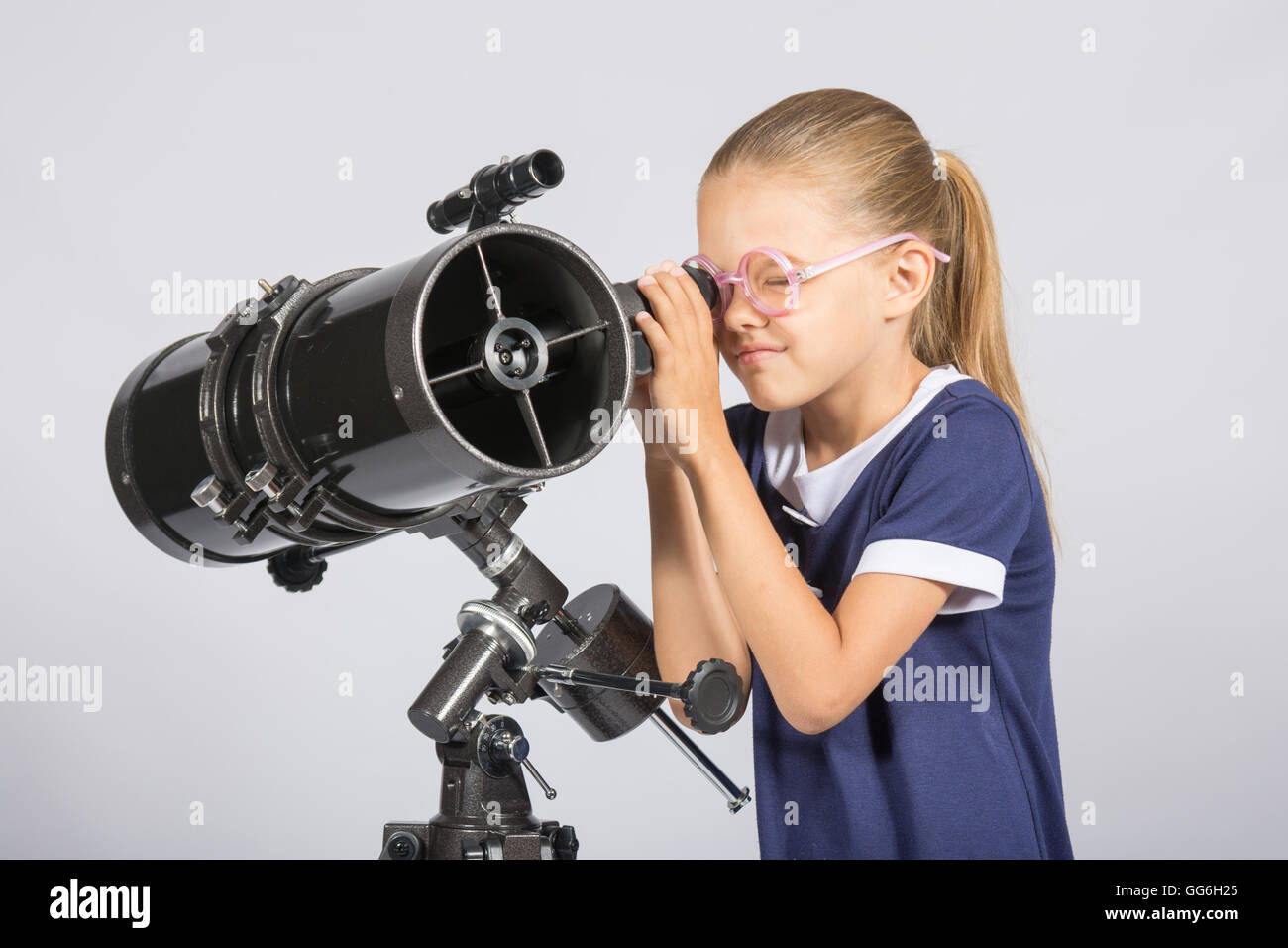 Sette anni di ragazza in bicchieri con interesse appare in un telescopio riflettore Foto Stock