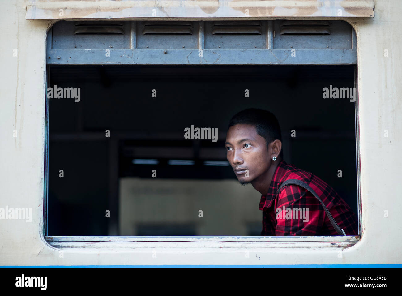 Un giovane uomo di attesa per il treno per lasciare la stazione centrale e la stazione ferroviaria, Yangon, Myanmar. Foto Stock