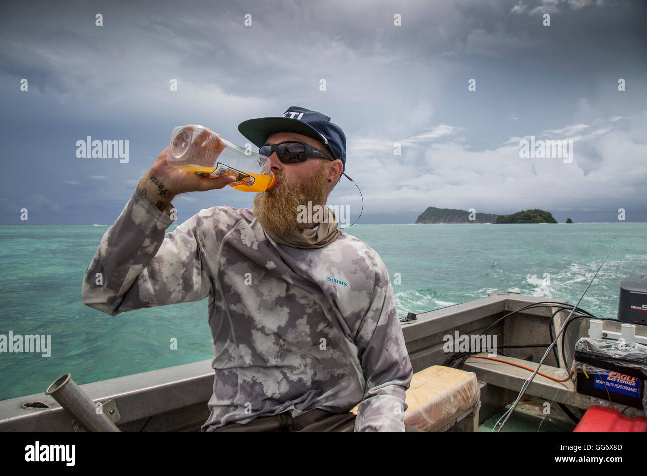 Il pescatore Jonathan Jones gode di una bevanda fredda locale di succo di arancia mentre scouting turni di pesca in Samoa. Foto Stock