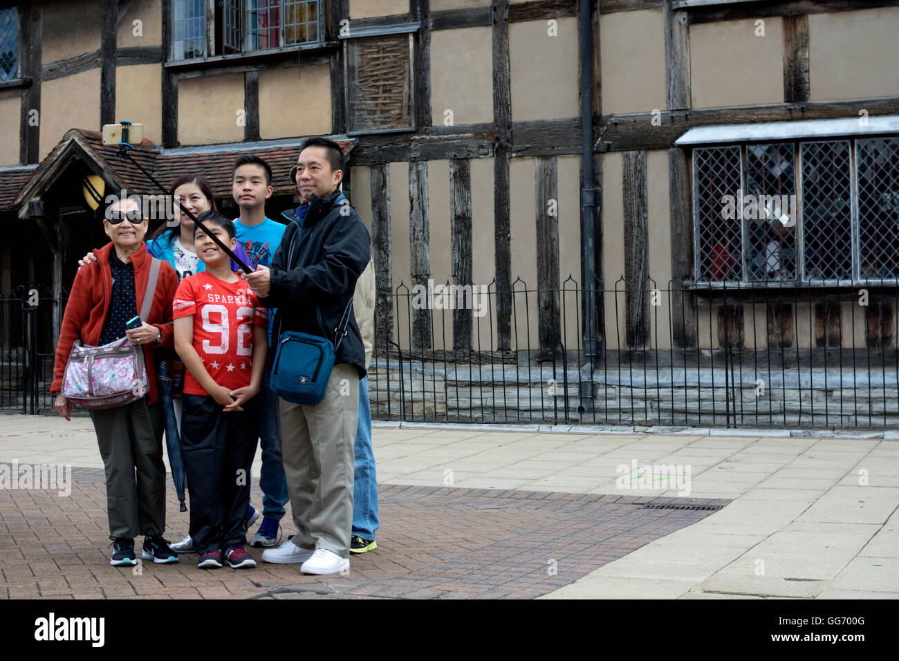 I turisti cinesi tenendo selfie fotografia al di fuori di William al luogo di nascita di Shakespeare, Stratford-upon-Avon, Warwickshire, Regno Unito Foto Stock