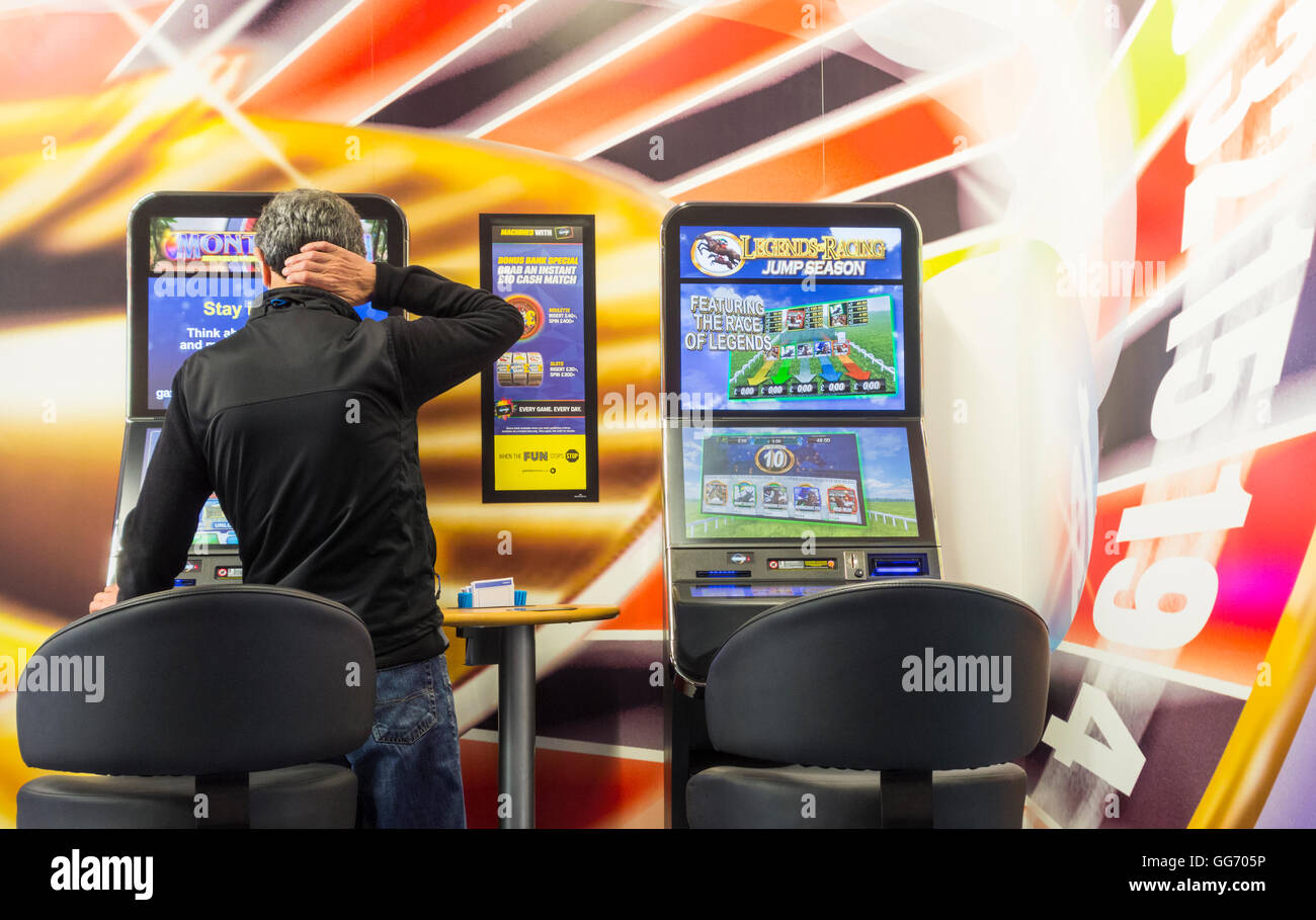 Uomo maturo utilizzando fixed odds Roulette macchina (FOBT fixed odds betting terminale) in Bookmakers. Inghilterra, Regno Unito Foto Stock