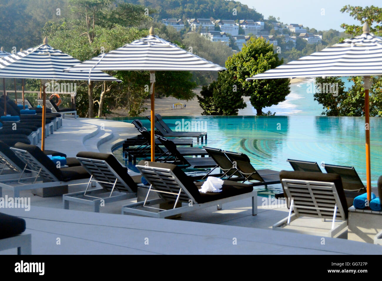 Sedie a sdraio vuote presso la piscina in una vacanza tropicale (Phuket) Foto Stock