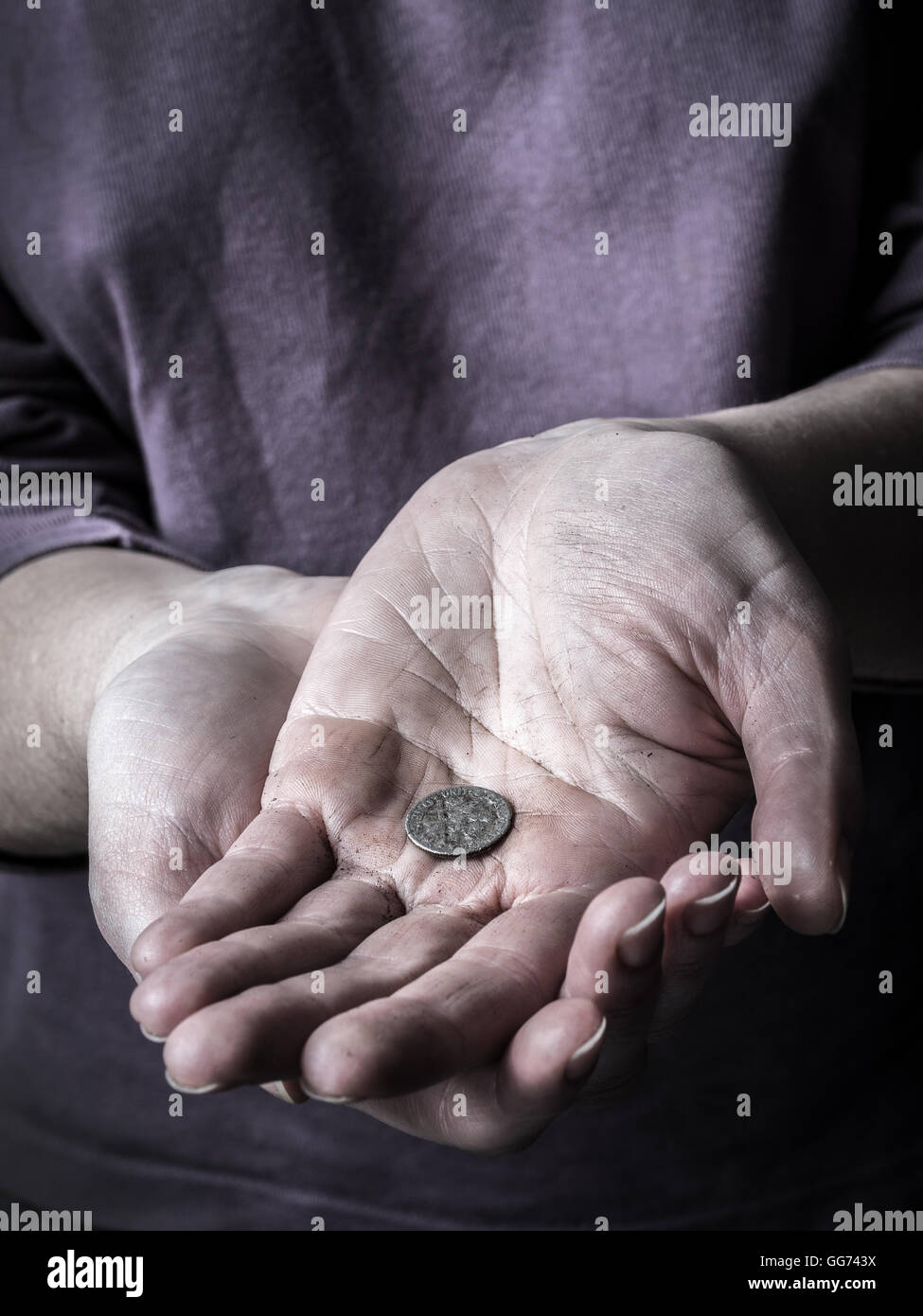 Primo piano della povera donna accattonaggio mani tenendo una moneta Foto Stock
