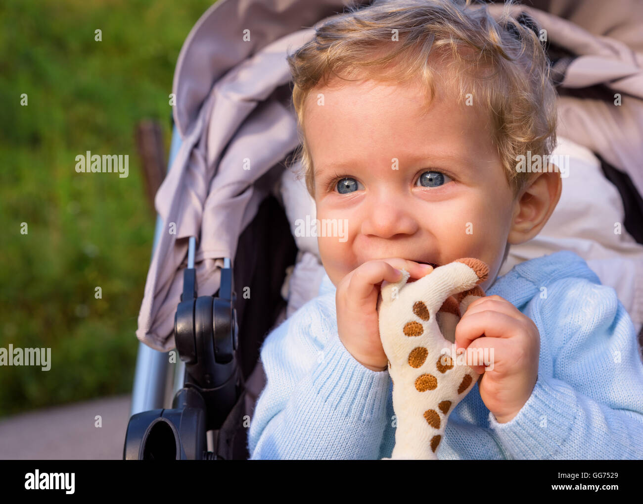 Bambino seduto nel passeggino felice a giocare con un giocattolo. Foto Stock