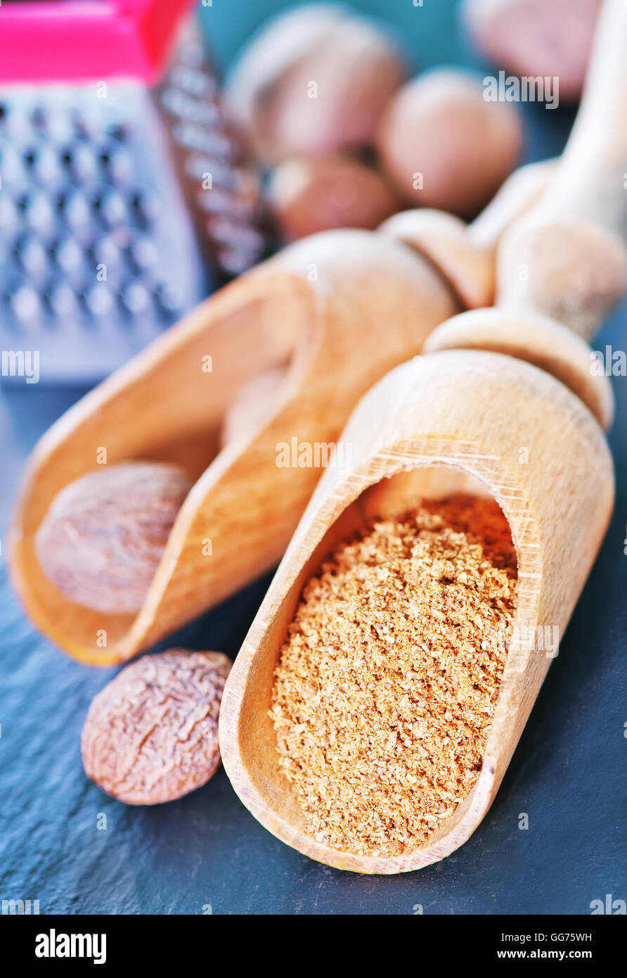 Noce moscata spice in cucchiaio di legno e su di una tavola Foto Stock