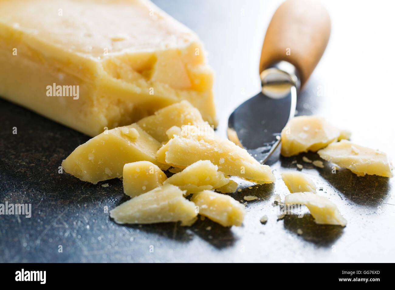 Il formaggio parmigiano con coltello sul vecchio tavolo da cucina. Foto Stock
