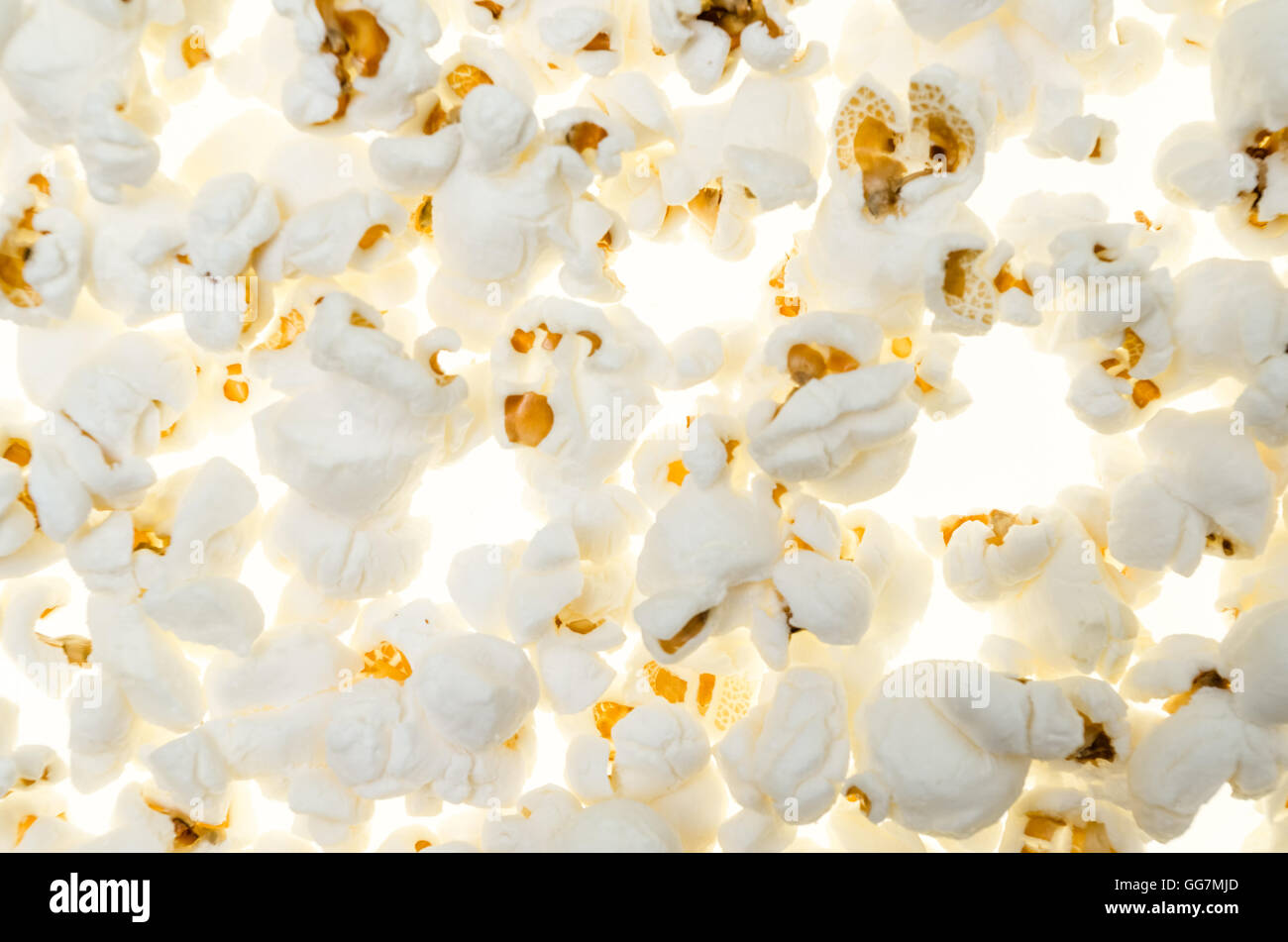 Sfondo con pop corn semi perfetta come una composizione insolita con i modelli e le texture su bianco Foto Stock