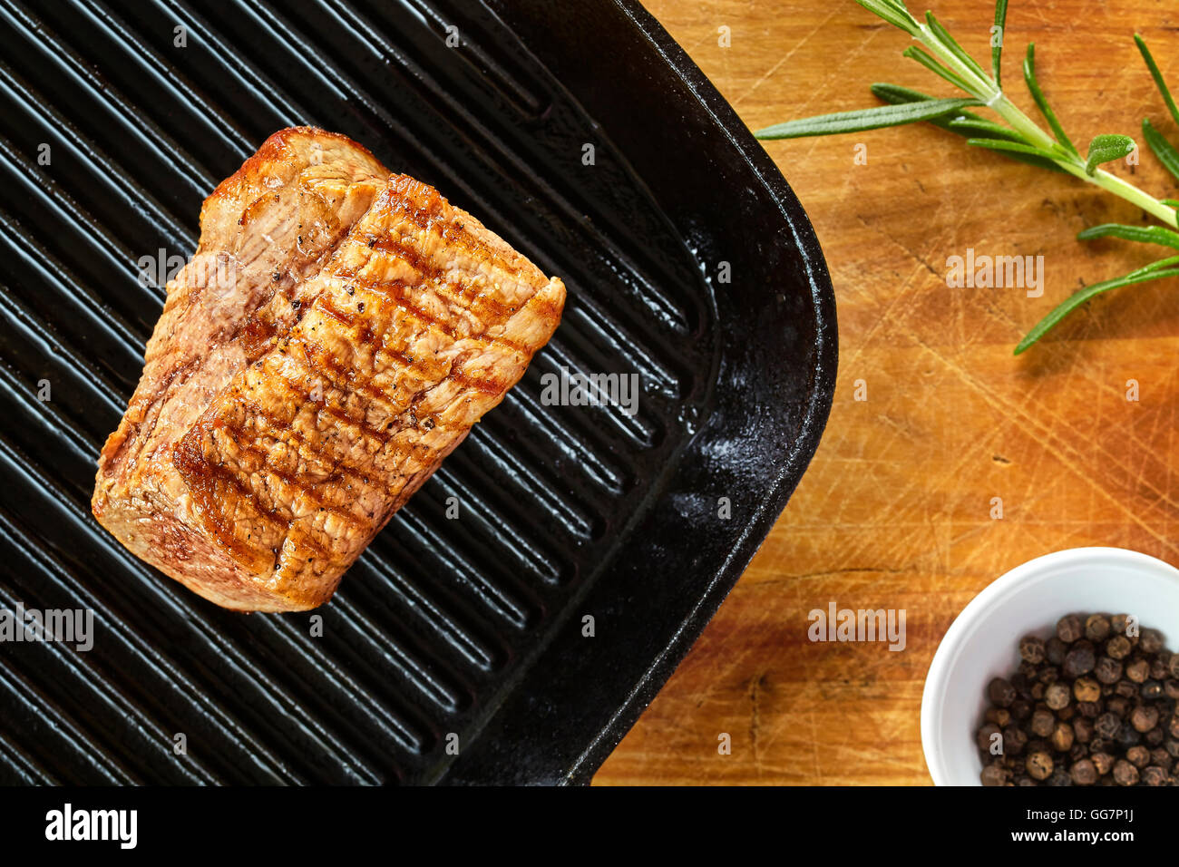 Chiudere l immagine di un arrosto di lombo di maiale in padella nera su un tavolo di legno. Foto Stock