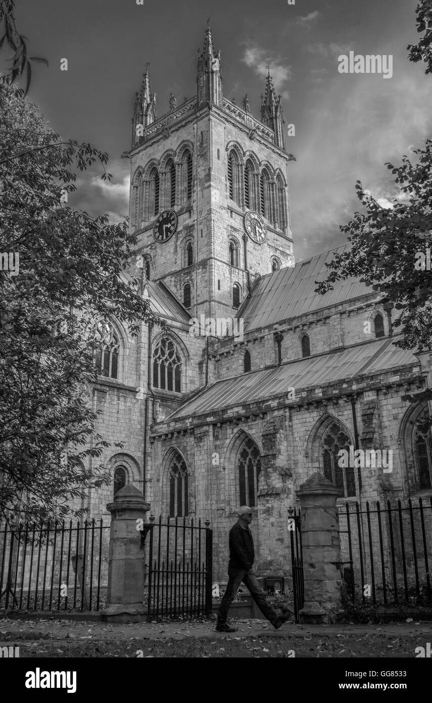 Uomo che cammina alacremente da Selby Abbey, North Yorkshire, Inghilterra, Regno Unito Foto Stock
