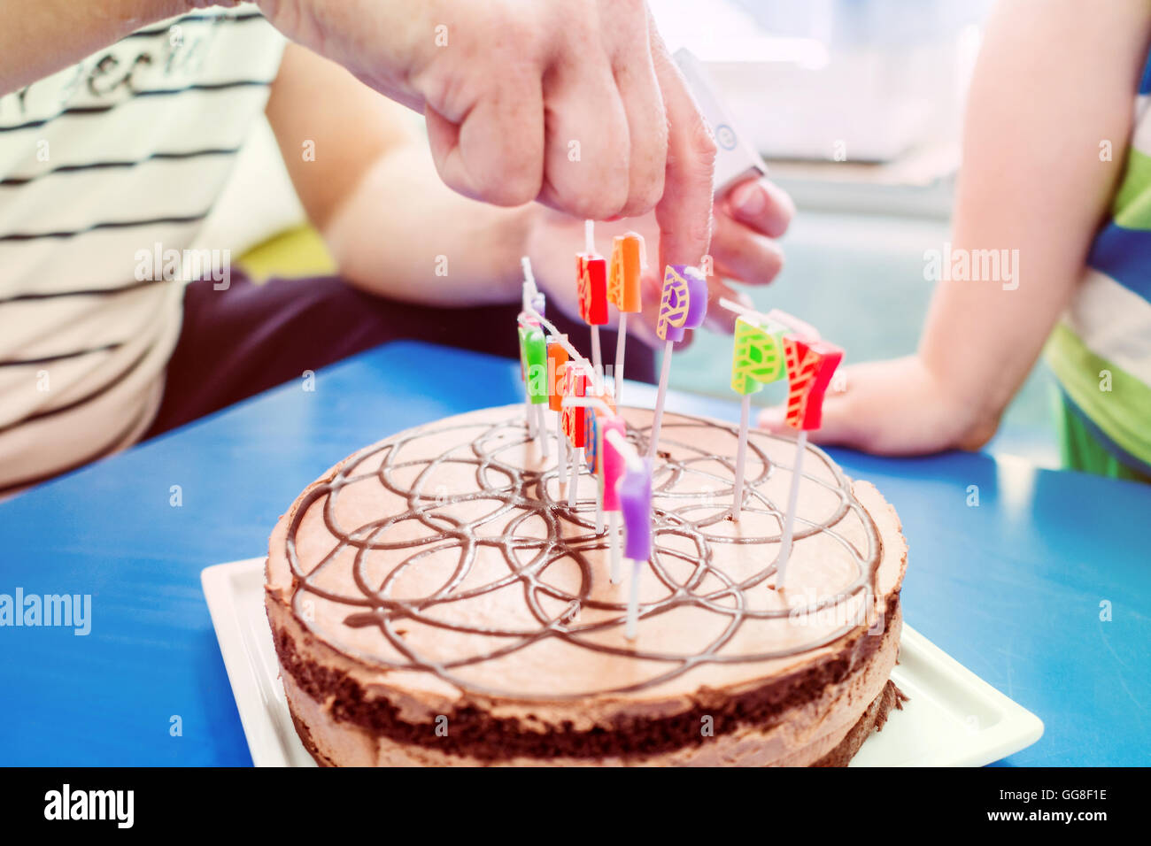 Festa di compleanno con torta al cioccolato con candele in forma di lettere  con il giovane ragazzo in movimento blu intorno a un tavolo di legno, happy  birthda Foto stock - Alamy