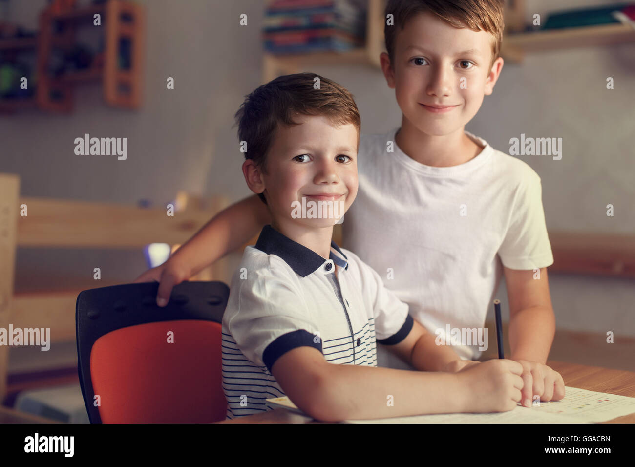 Piccolo scolaro con il fratello aiuta a scrivere i compiti a scrivania Foto Stock