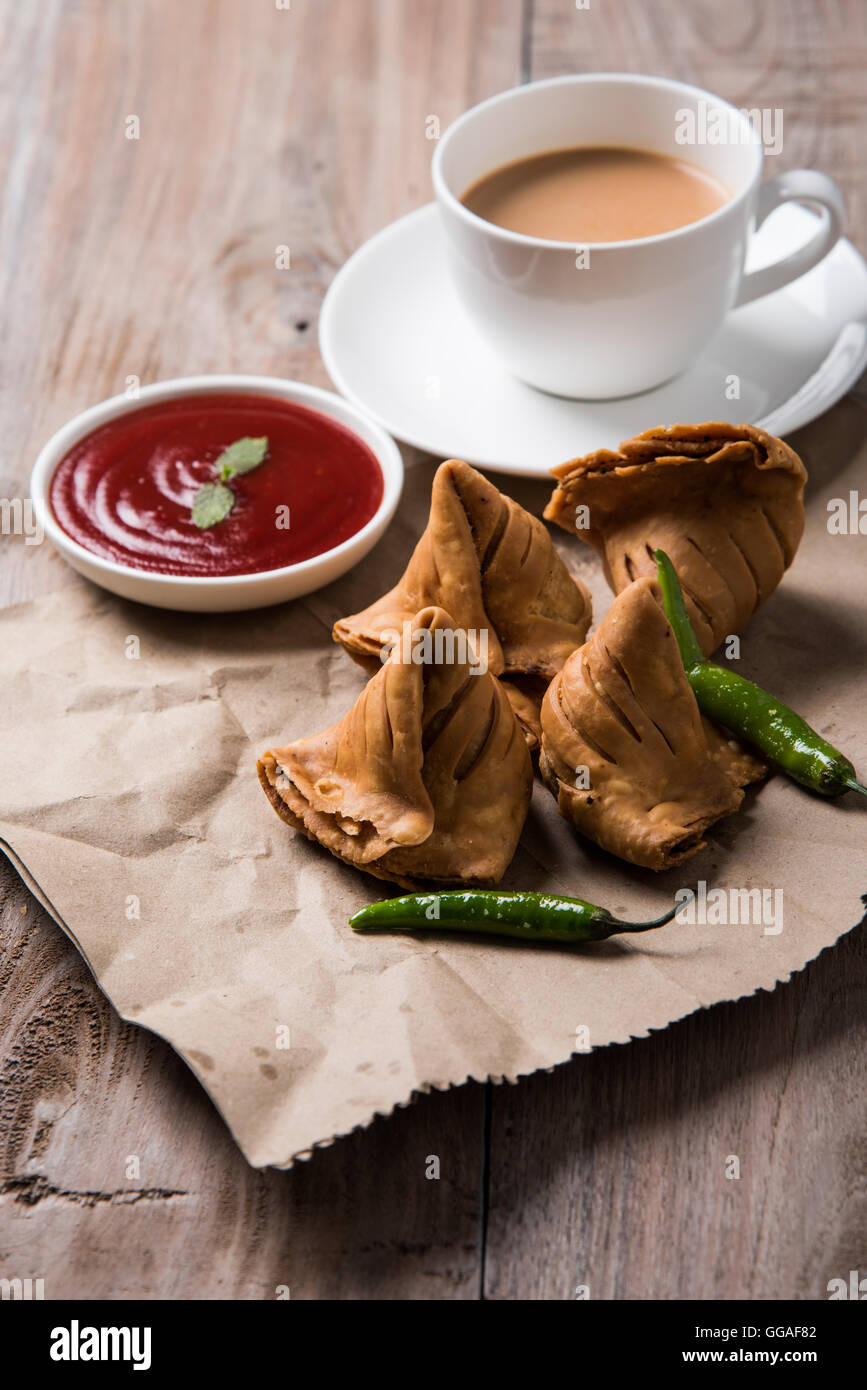 Samosa snack di ketchup e tè caldo, fresco samosas con ketchup e caldo chai pronti per la prima colazione Foto Stock