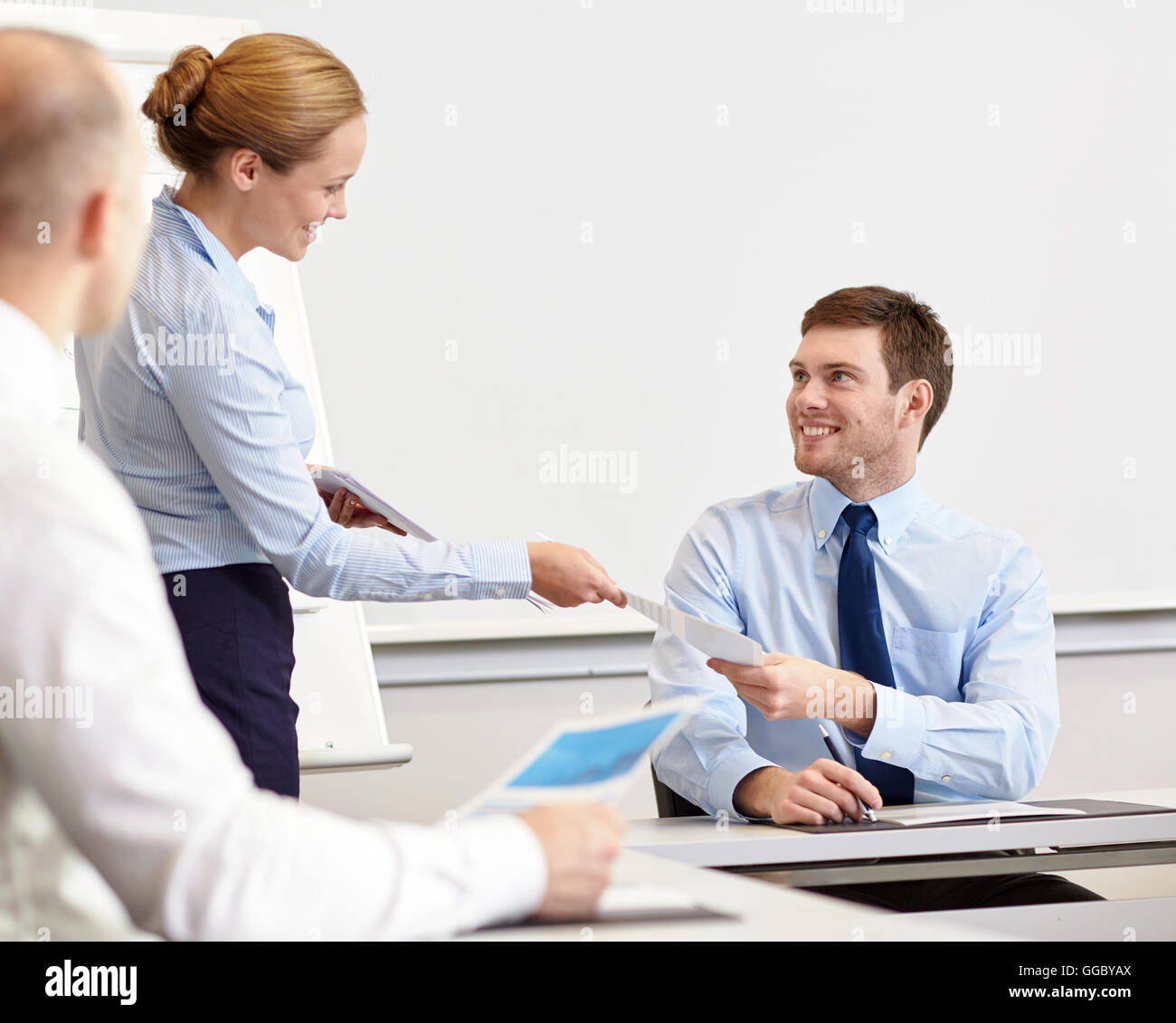 Donna sorridente dando carte per uomo in ufficio Foto Stock