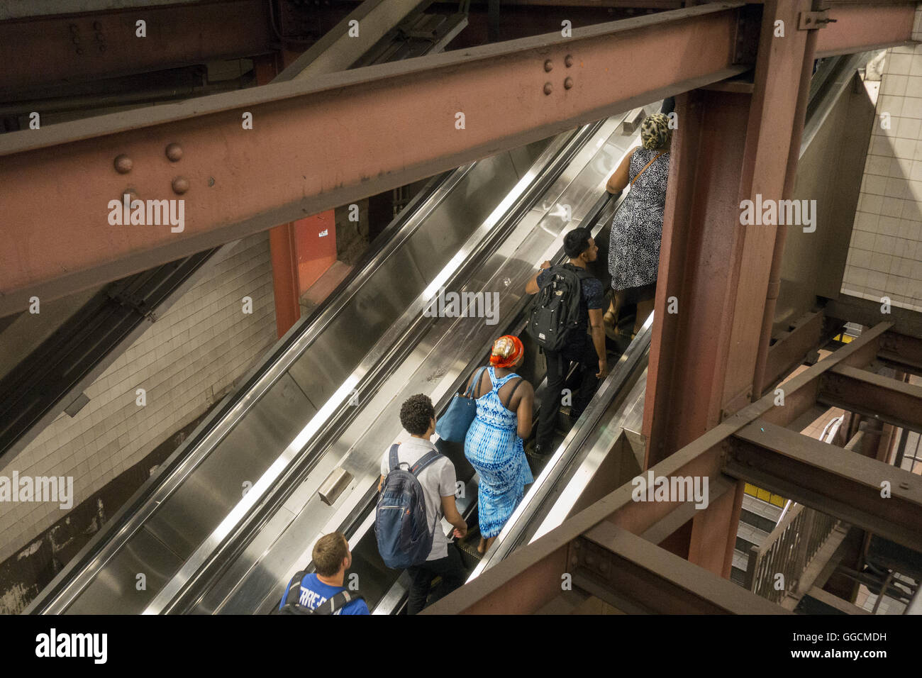 Le persone fanno la loro uscita della 34th St. stazione della metropolitana su una scala mobile di Herald Square attraverso pesanti fascio di costruzione. Foto Stock