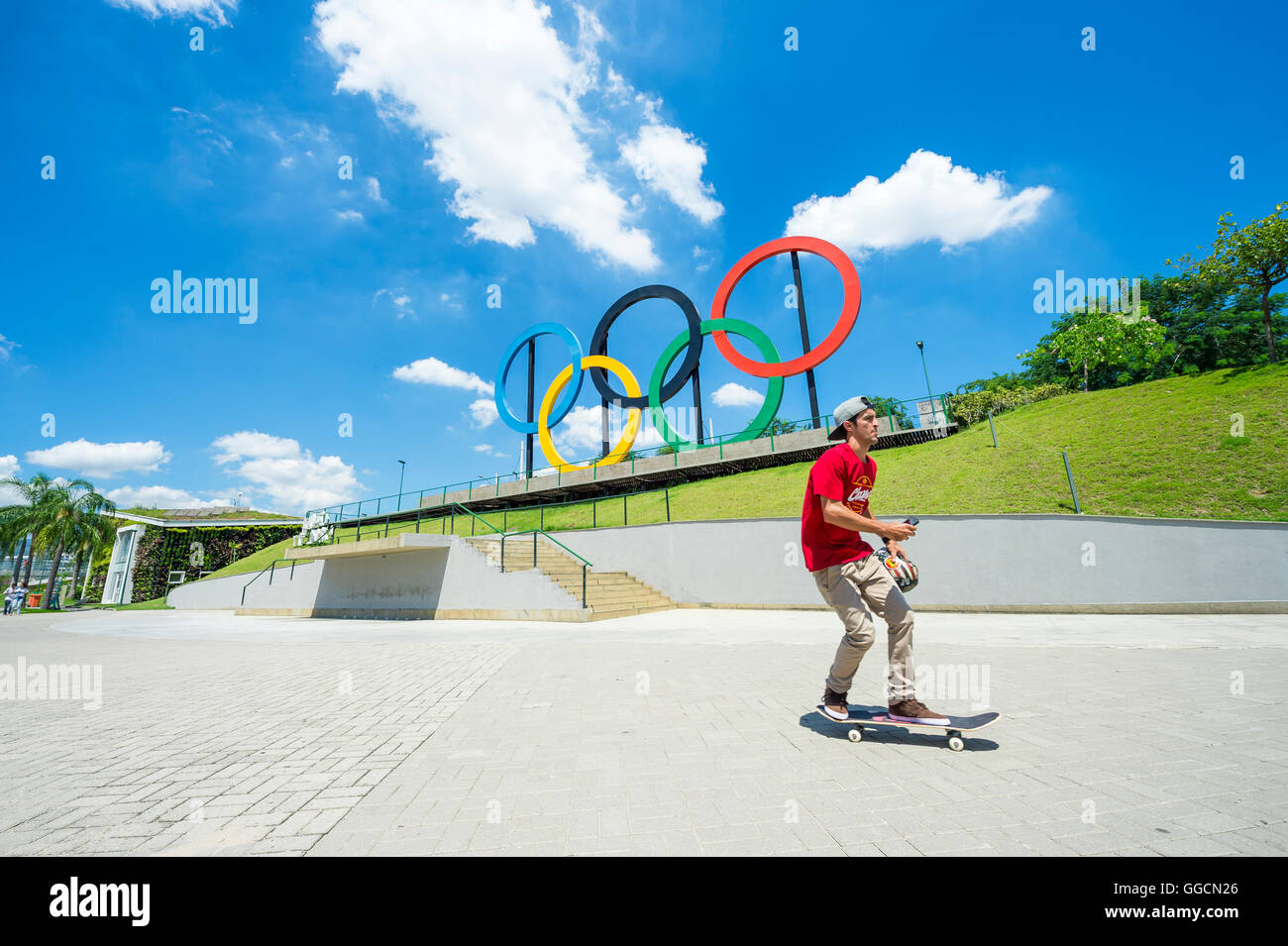 RIO DE JANEIRO - MARZO 18, 2016: un giovane guidatore di skateboard pattini di fronte anelli olimpici installato per il 2016 giochi d'estate. Foto Stock