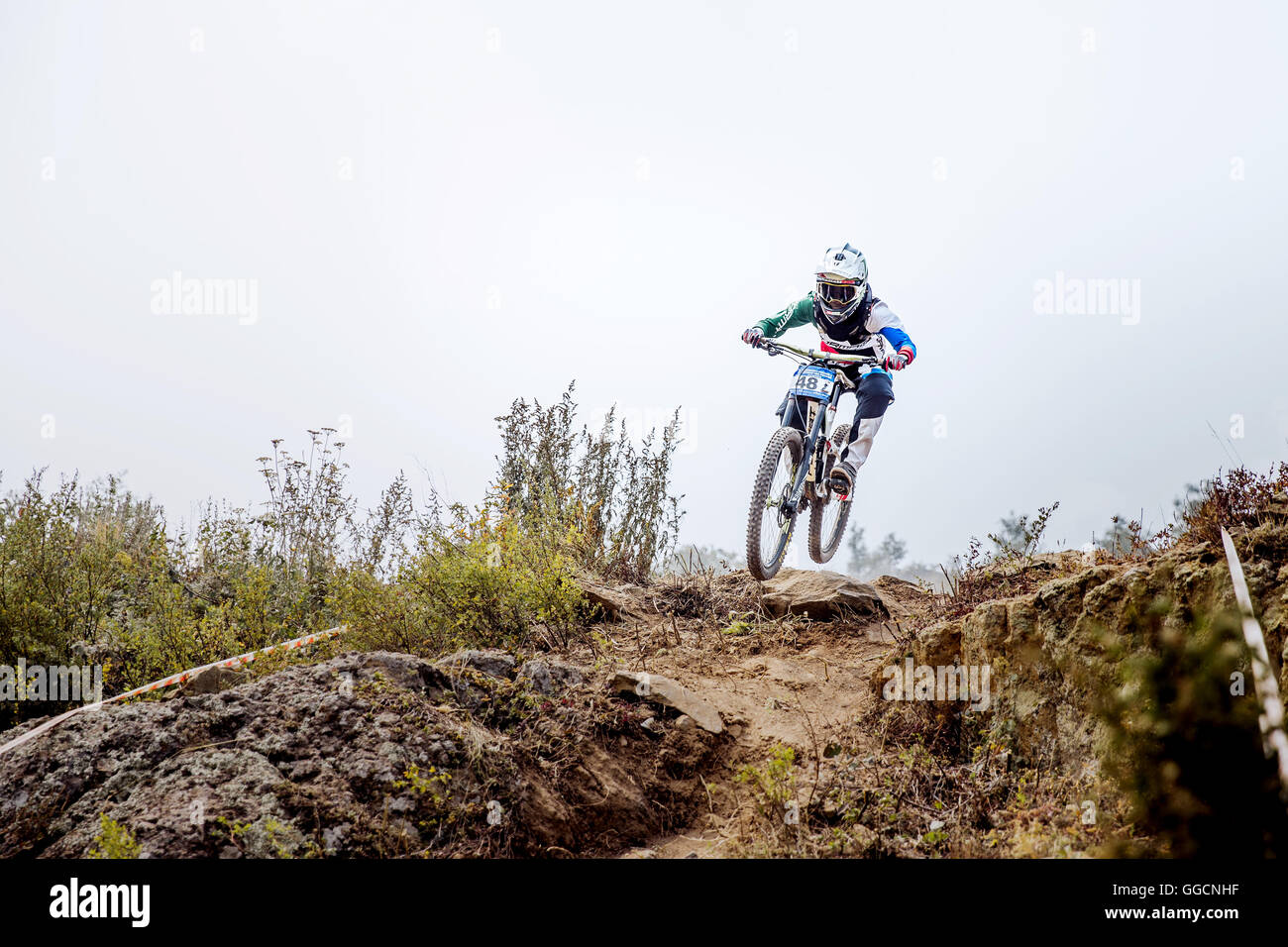 Uomo atleta estreme su Bike jump sulla cima della montagna durante il campionato nazionale in discesa Foto Stock