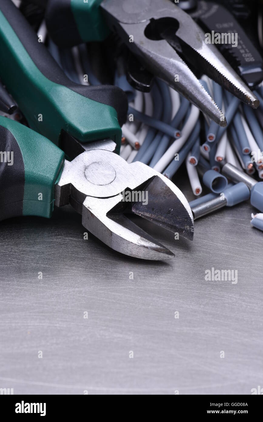 Strumenti per elettricista e i cavi grigio sulla superficie metallica Foto Stock